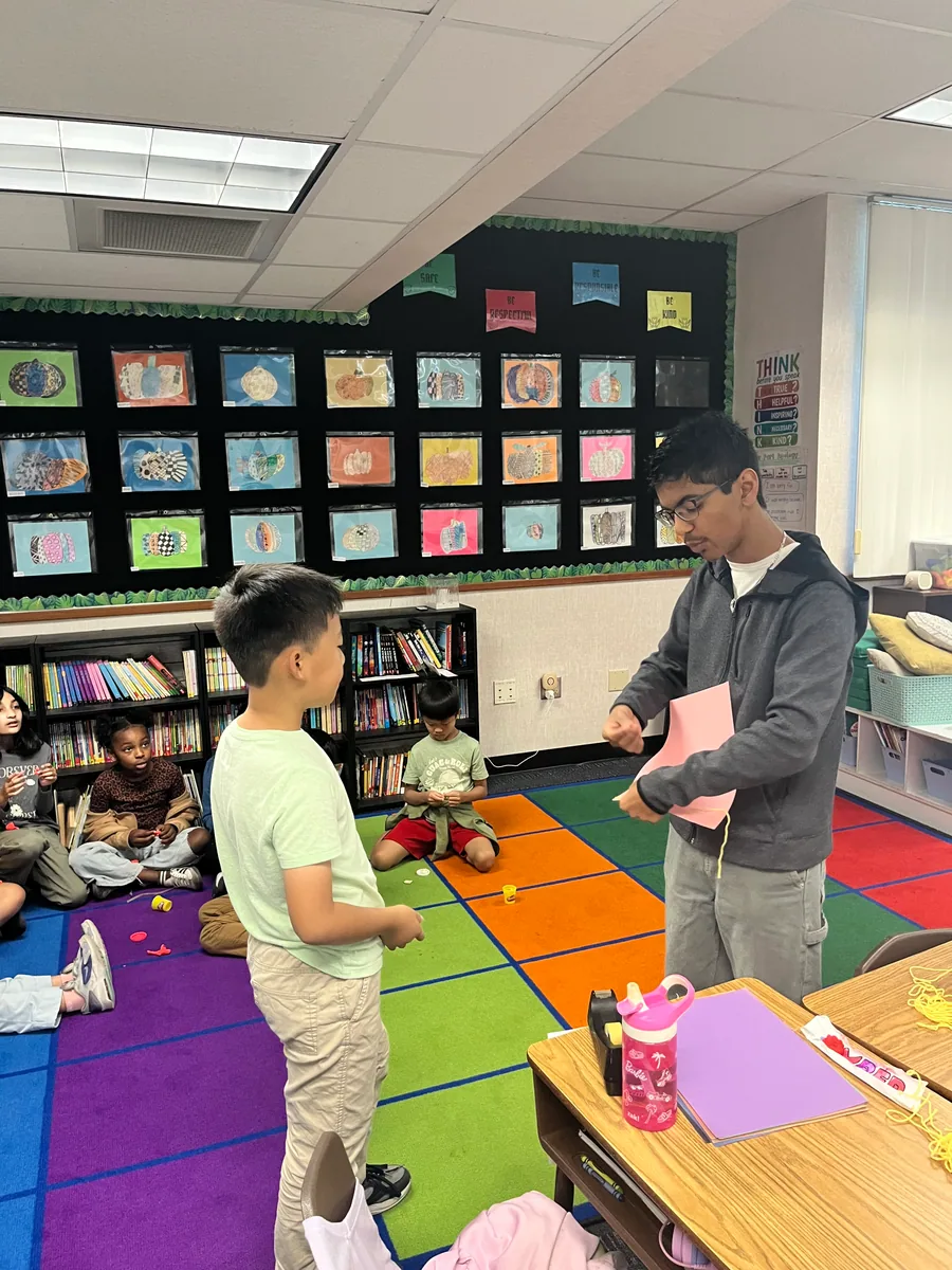 Rishi Shah guiding a student through a classroom engineering activity